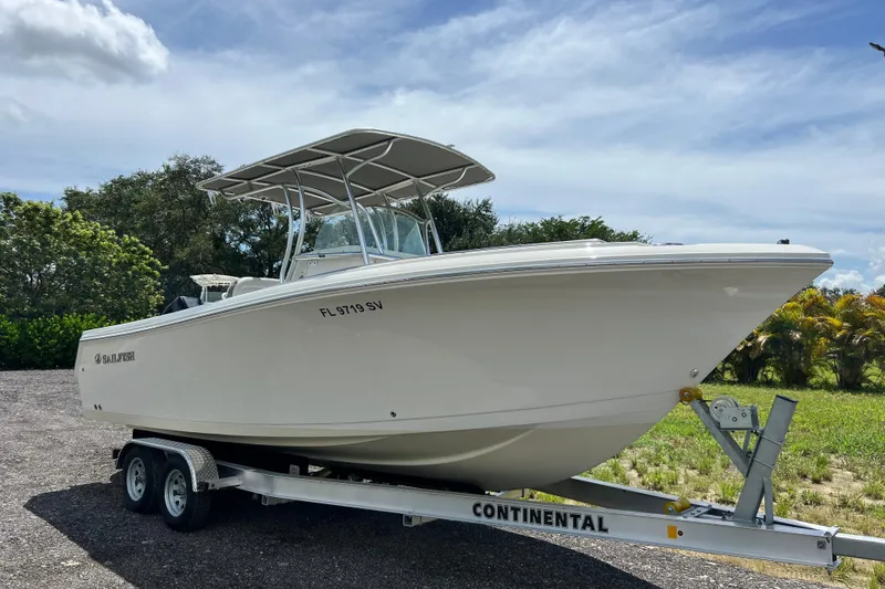Slide: The Image of 2021 Sailfish 242 CC boat on trailer, parked outdoors under a cloudy sky. - 2