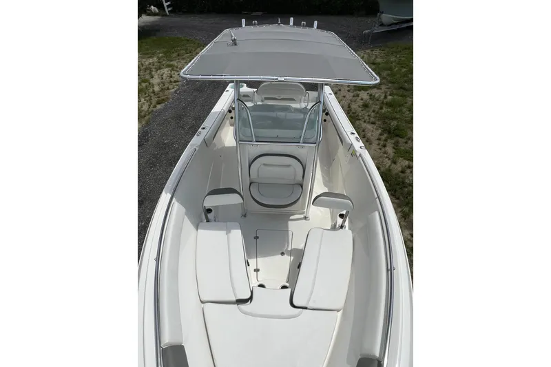 Slide: The Image of 2021 Sailfish 242 CC boat interior with seating and canopy, parked on grass. - 26