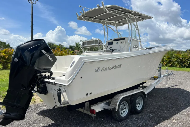 Slide: The Image of 2021 Sailfish 242 CC boat on trailer with Mercury engine, parked outdoors under blue sky. - 29