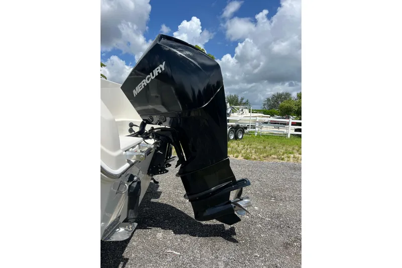 Slide: The Image of 2021 Sailfish 242 CC boat with Mercury outboard motor, parked outdoors under cloudy sky. - 31