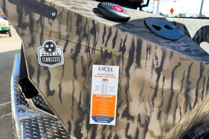 Slide: The Image of 2026 Excel 220 Bay Pro Elite boat displayed at indoor exhibition, featuring camo design and Suzuki engine. - 16