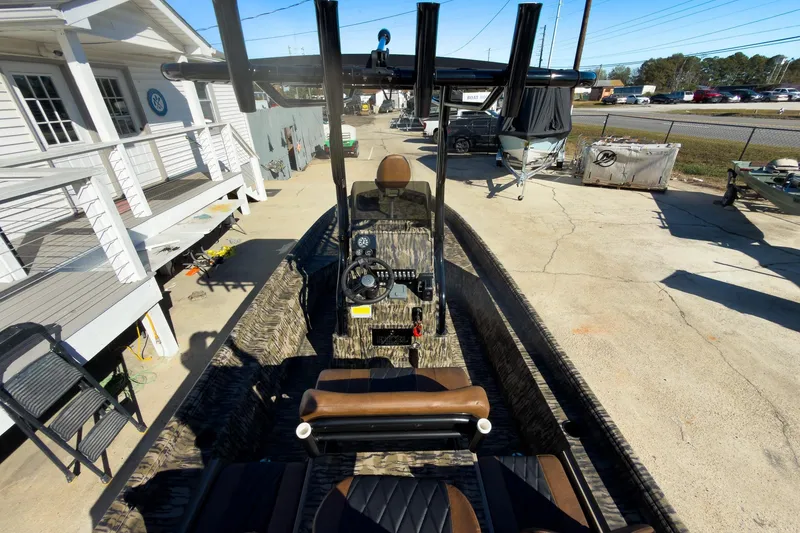 Slide: The Image of 2026 Excel Bay Pro Elite 220 boat, camo design, parked outdoors near a white building. - 32