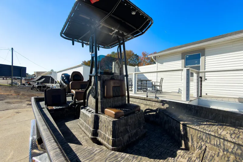 Slide: The Image of 2026 Excel Bay Pro Elite 220 boat with camo design, parked outdoors under clear blue sky. - 34
