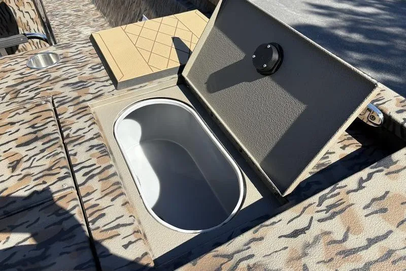 Slide: The Image of 2026 Xpress H210B Bay boat with open storage compartment, camo pattern design. - 10