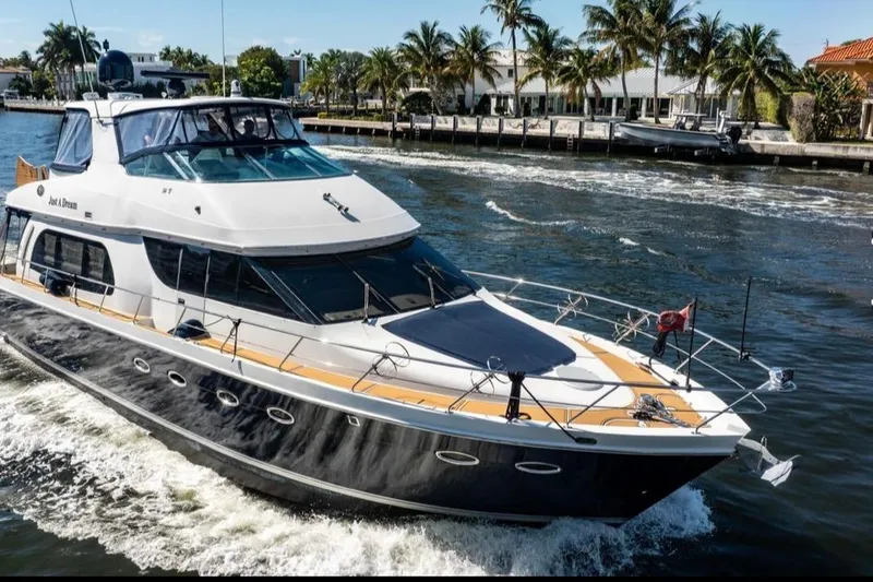 Slide: The Image of 2005 Carver 56 Voyager yacht cruising on a sunny day, surrounded by palm trees. - 2