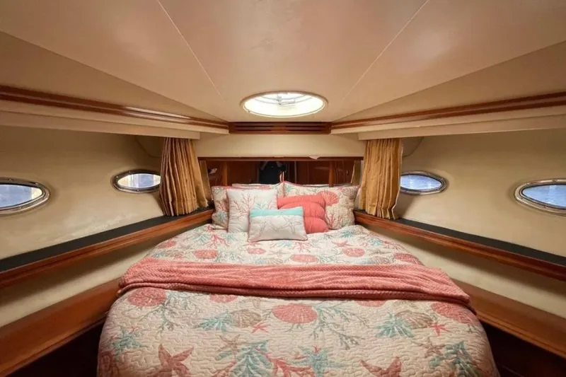 Slide: The Image of Luxurious bedroom interior of 2005 Carver 56 Voyager yacht with cozy bedding and porthole windows. - 23