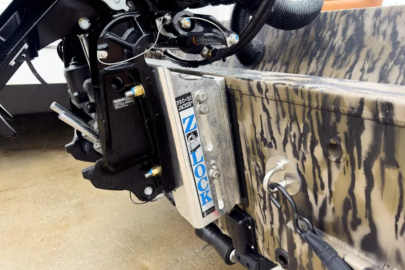 Slide: The Image of 2026 Excel EX203C Crappie & Bass boat on trailer, camo design, parked near white building. - 6