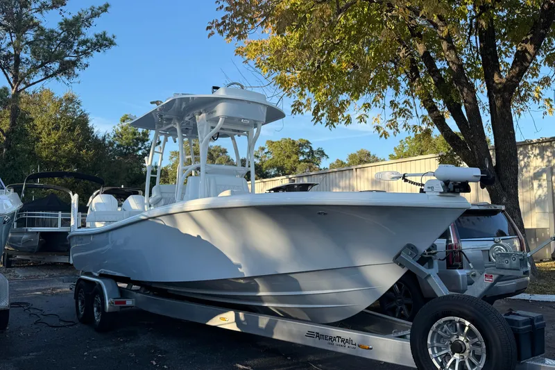 Slide: The Image of 2022 Yellowfin 26 Hybrid boat on trailer, parked outdoors under trees. - 0