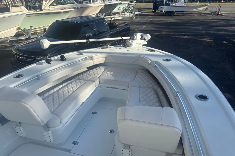 Slide: The Image of 2022 Yellowfin 26 Hybrid boat with luxurious seating and sleek design in a marina setting. - 6