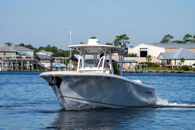 Slide: The Image of 2017 Sailfish 290 CC boat cruising on a calm waterfront near docks and buildings. - 10