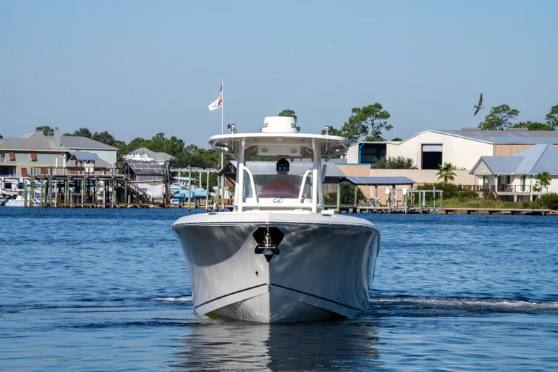 Slide: The Image of 2017 Sailfish 290 CC boat cruising on a calm waterfront near docks and buildings. - 11