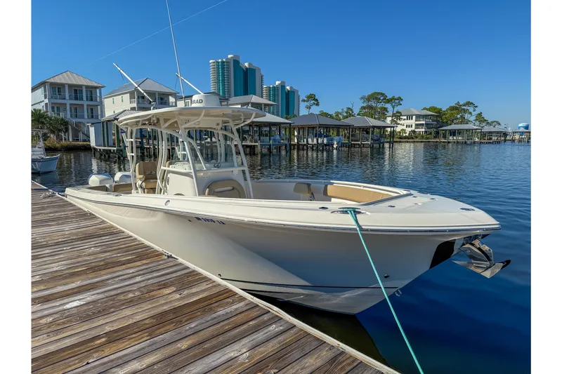 Slide: The Image of 2017 Sailfish 290 CC boat docked at marina with waterfront buildings in background. - 15