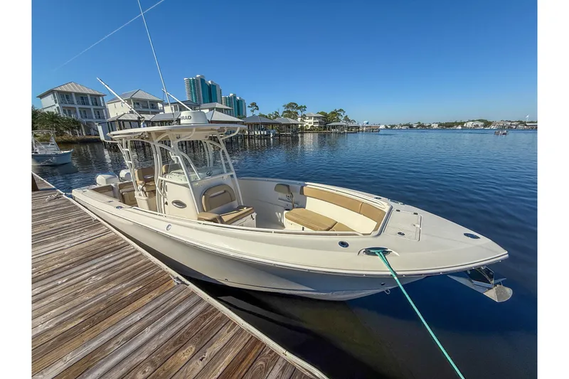Slide: The Image of 2017 Sailfish 290 CC boat docked by waterfront homes under clear blue sky. - 16
