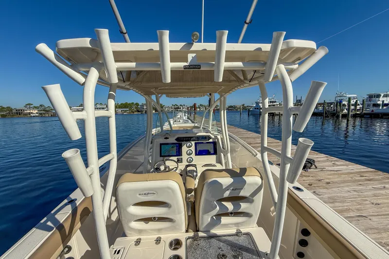 Slide: The Image of 2017 Sailfish 290 CC boat docked, featuring helm with navigation screens and rod holders. - 22