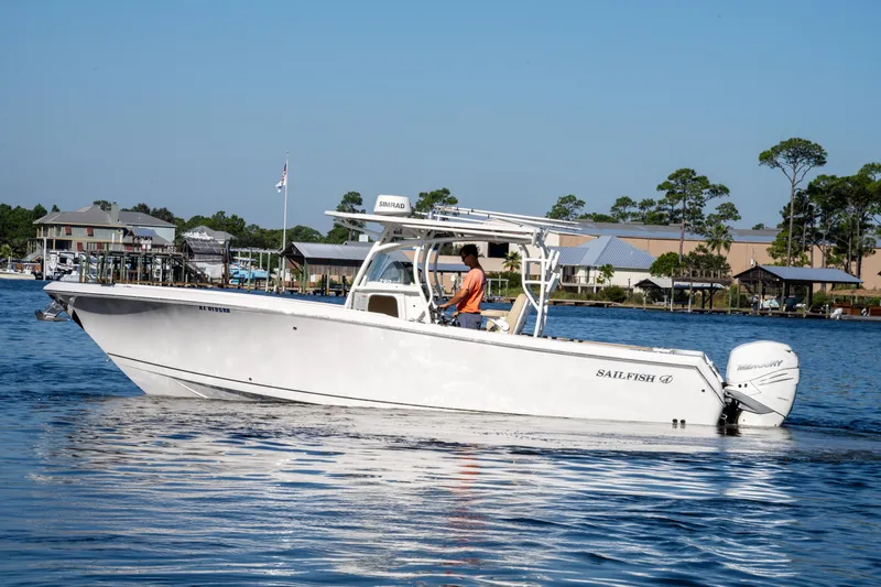 Slide: The Image of 2017 Sailfish 290 CC boat cruising on a calm lake near waterfront homes. - 5