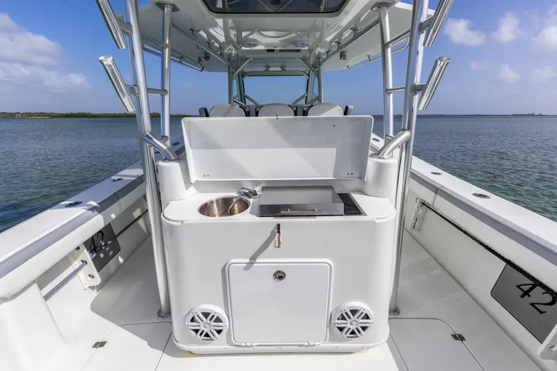 Slide: The Image of 2018 Yellowfin 42 Offshore boat with onboard sink and grill, set against a serene water backdrop. - 19