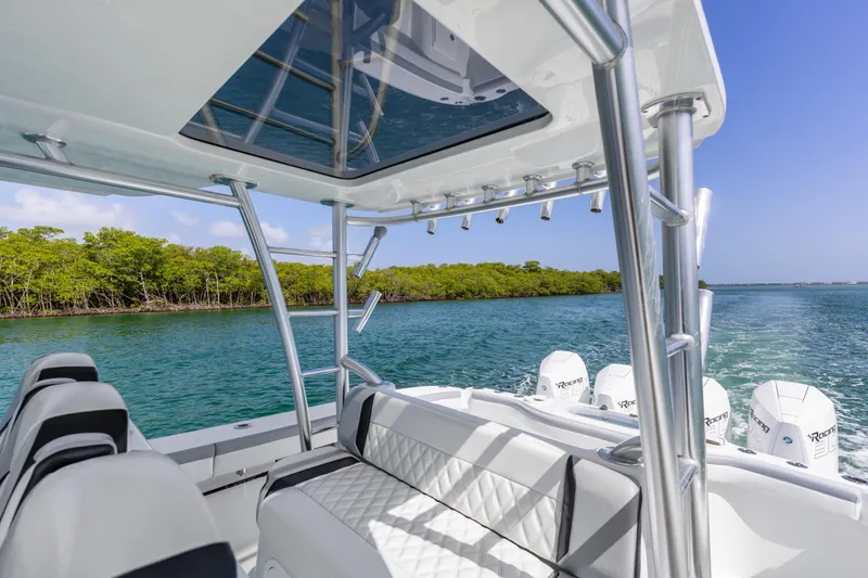 Slide: The Image of 2018 Yellowfin 42 Offshore boat cruising on clear blue water near lush green shoreline. - 22