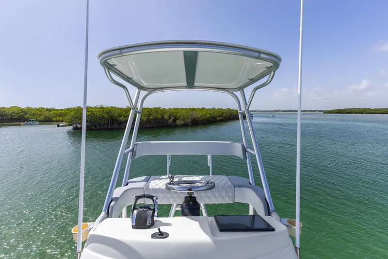 Slide: The Image of 2018 Yellowfin 42 Offshore boat navigating serene waters with lush green shoreline. - 37