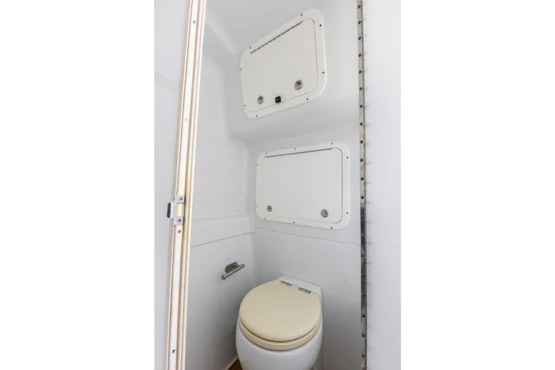 Slide: The Image of 2018 Yellowfin 42 Offshore boat bathroom with white toilet and storage compartments. - 43