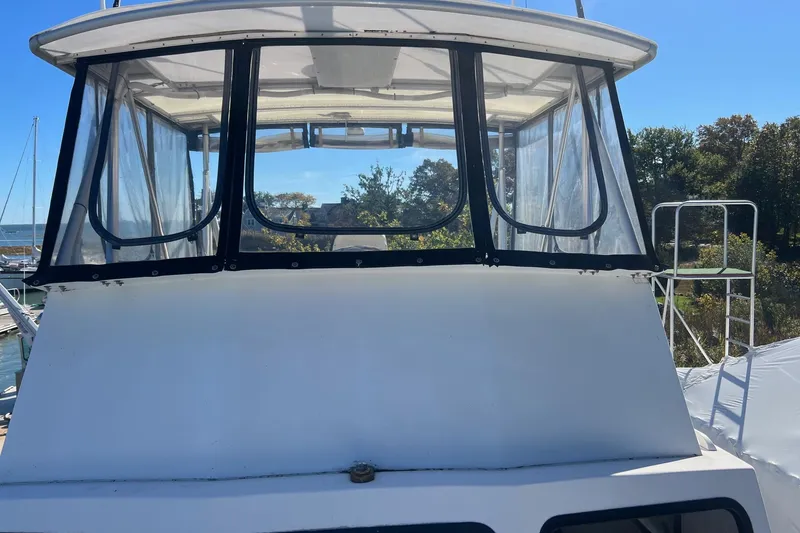 Slide: The Image of 1995 Young Brothers 38 Fly Bridge boat with clear enclosure, docked in a marina. - 3