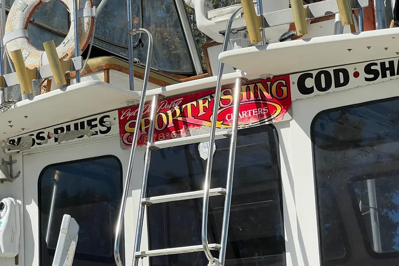 Slide: The Image of 1995 Young Brothers 38 Fly Bridge boat with sportfishing charter signage and ladder. - 8