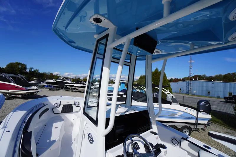 Slide: The Image of 2026 Tidewater 220 LXF boat with blue T-top and modern console, docked outdoors. - 18