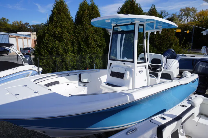 Slide: The Image of 2026 Tidewater 220 LXF boat with blue hull and T-top in a marina setting. - 2