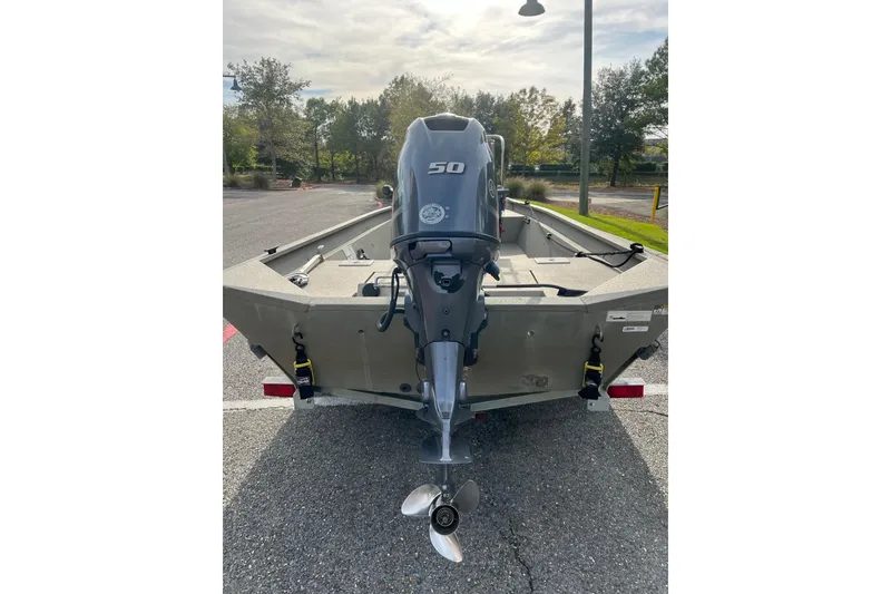 Slide: The Image of 2014 Alumacraft 1756 All Weld MV CC boat with 50 HP outboard motor, parked outdoors. - 2