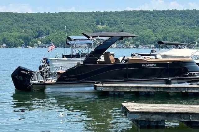 Slide: The Image of 2025 Harris Grand Mariner SL 230 pontoon boat docked on a scenic lake. - 2