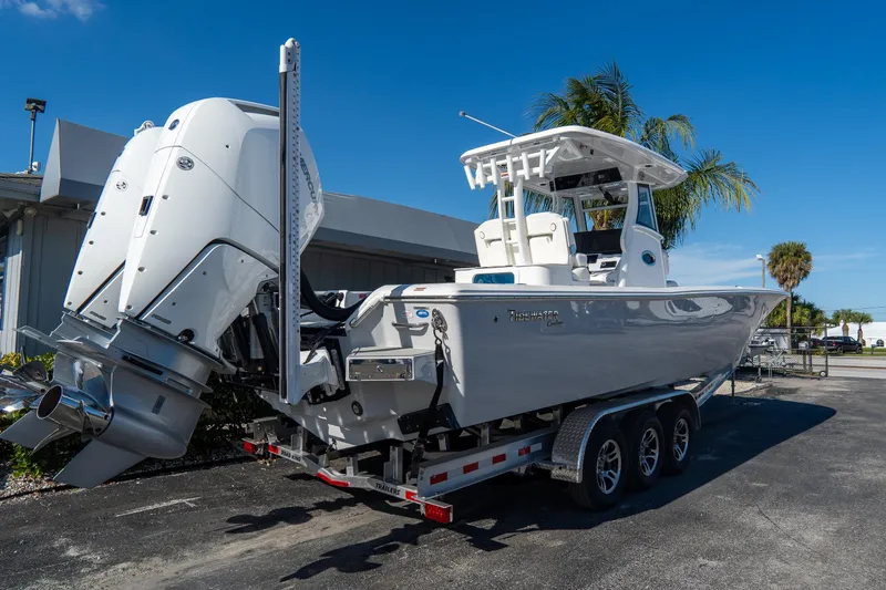 Slide: The Image of 2026 Tidewater 3100 Carolina Bay boat on trailer, featuring dual engines, under clear blue sky. - 3