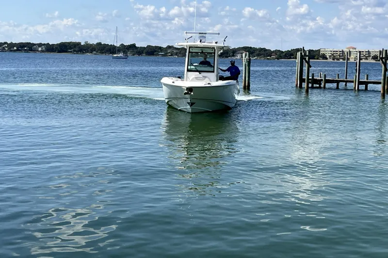 Slide: The Image of 2012 Boston Whaler 320 Outrage boat navigating calm waters near a dock. - 1