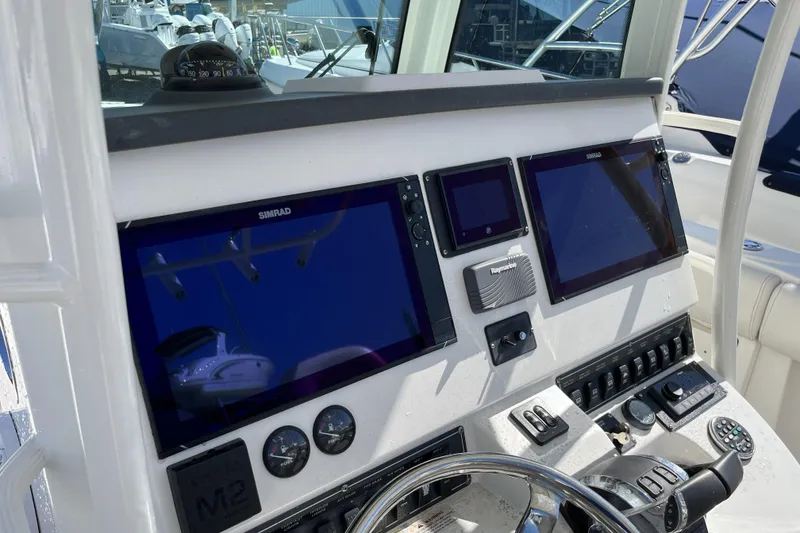 Slide: The Image of 2012 Boston Whaler 320 Outrage dashboard with Simrad displays and navigation controls. - 6