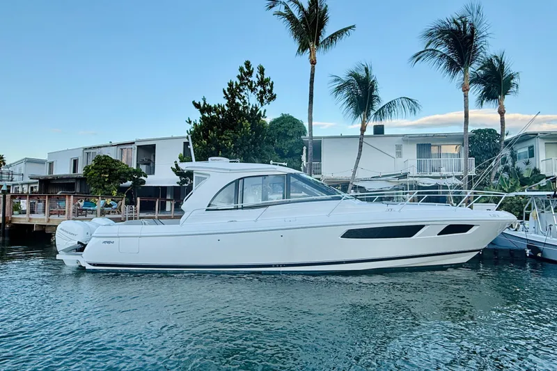 Slide: The Image of 2021 Intrepid 410 Evolution yacht docked near waterfront homes and palm trees. - 2