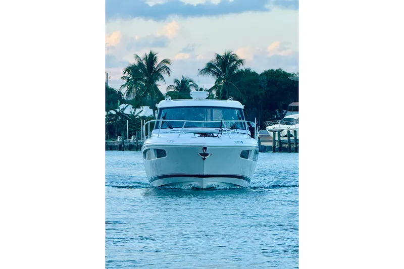 Slide: The Image of Front view of 2021 Intrepid 410 Evolution yacht on water, with palm trees in background. - 3