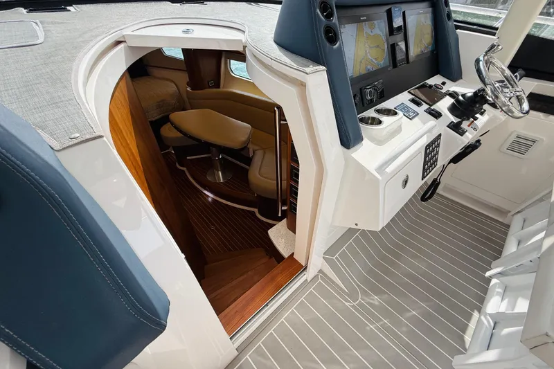 Slide: The Image of 2021 Intrepid 410 Evolution yacht interior with helm, navigation screens, and cabin entrance. - 34