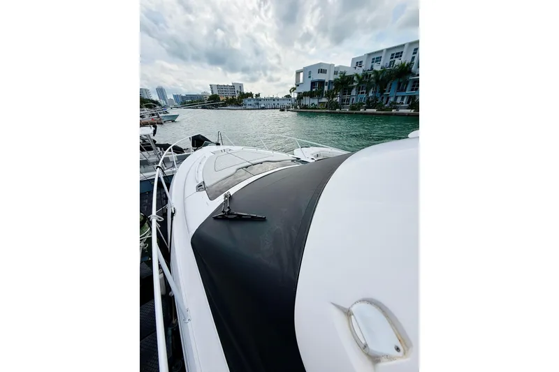 Slide: The Image of 2021 Intrepid 410 Evolution yacht docked by waterfront buildings under cloudy sky. - 8