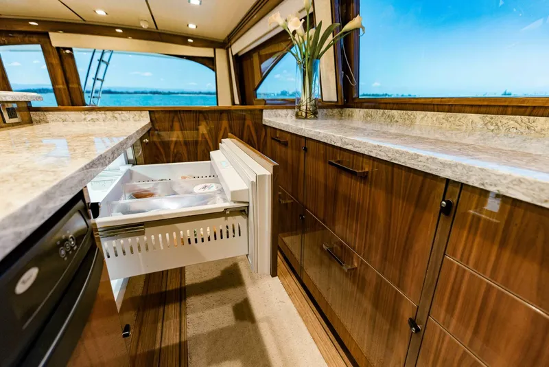 Slide: The Image of Luxurious Viking 72 yacht kitchen interior with open drawer, marble countertops, and ocean view. - 14