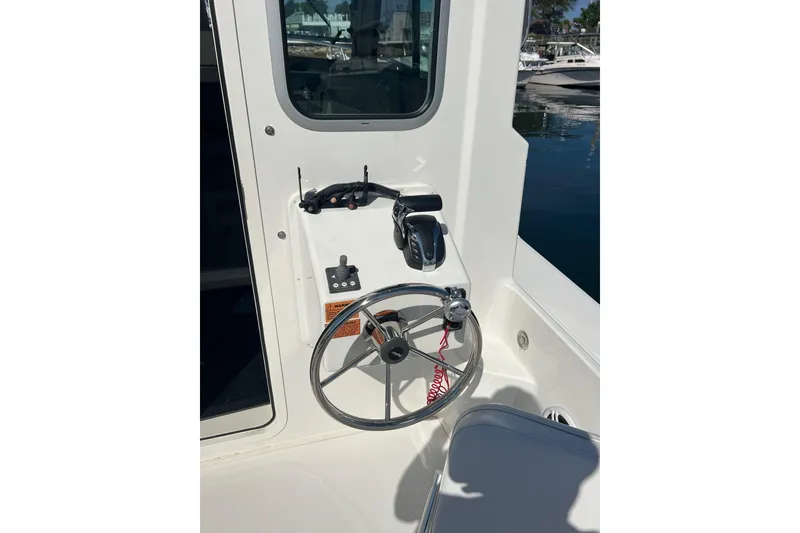 Slide: The Image of 2023 Parker 2520 XLD Sport Cabin steering wheel and controls in a marina setting. - 8