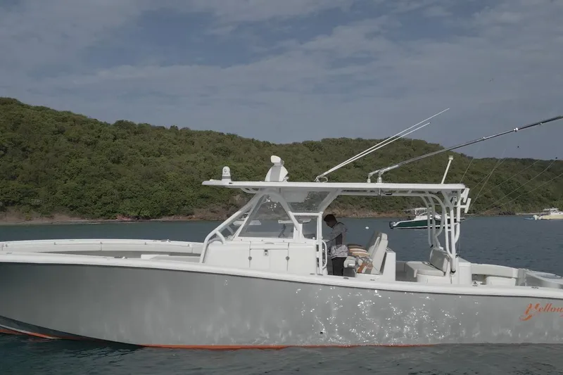 Slide: The Image of 2015 Yellowfin 42 Offshore boat on calm water near a lush green shoreline. - 6