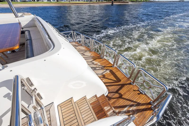 Slide: The Image of Luxurious 2003 Johnson 87' Motor Yacht deck with elegant wood finish and scenic water view. - 12