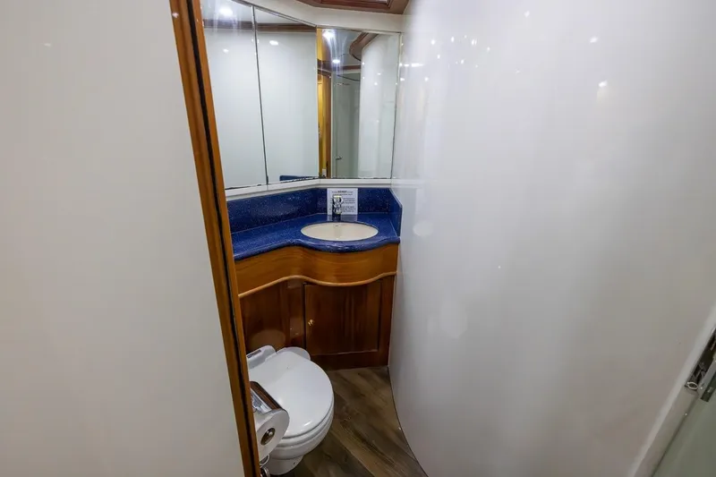 Slide: The Image of Bathroom interior of 2003 Johnson 87' Motor Yacht with blue countertop and wooden cabinetry. - 63