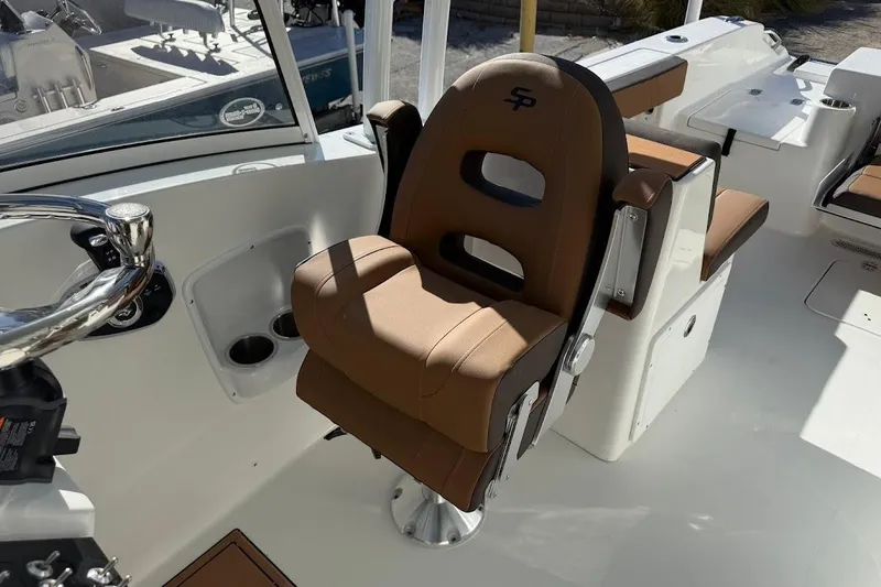 Slide: The Image of 2026 Sea Pro 240 Dual Console boat interior with brown captain's chair and steering wheel. - 21