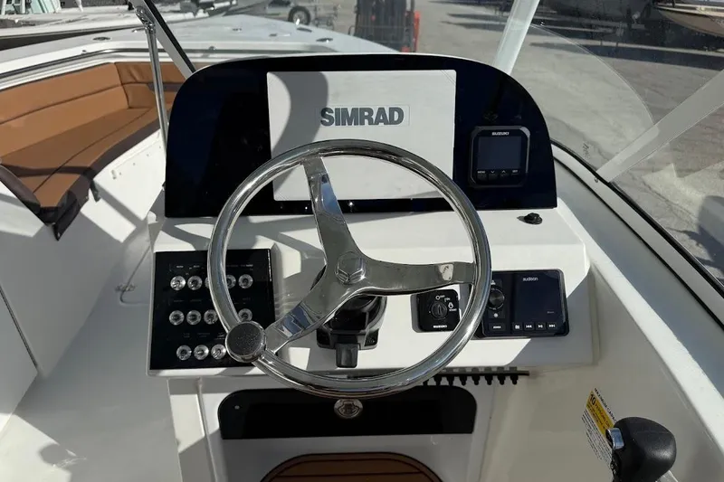 Slide: The Image of 2026 Sea Pro 240 Dual Console boat dashboard with steering wheel and Simrad electronics. - 23