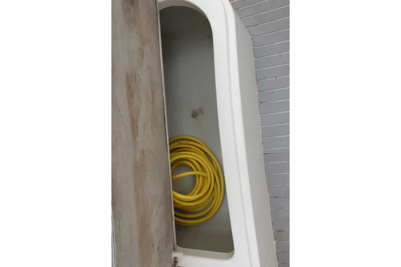 Slide: The Image of Storage compartment with yellow hose on 2002 Rinker Fiesta Vee 250 boat. - 15