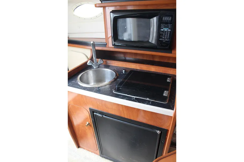 Slide: The Image of 2002 Rinker Fiesta Vee 250 boat kitchenette with sink, microwave, and stove. - 27