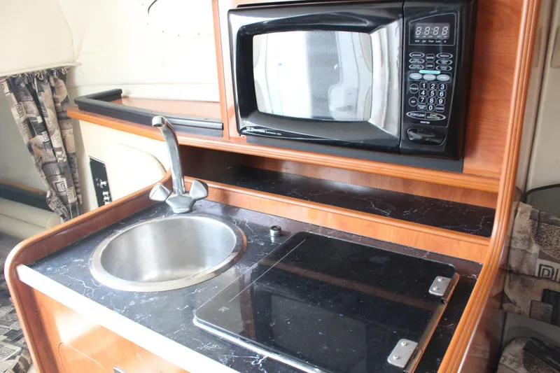 Slide: The Image of 2002 Rinker Fiesta Vee 250 boat kitchenette with sink, microwave, and stove. - 29