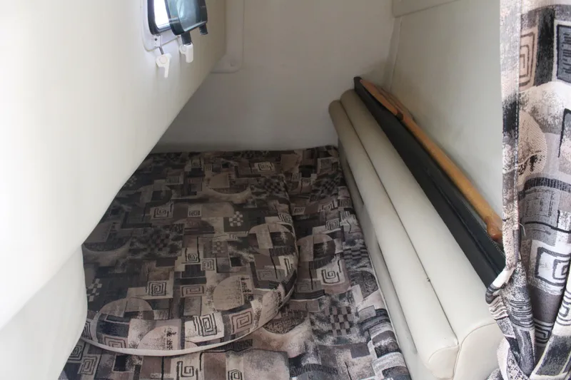 Slide: The Image of 2002 Rinker Fiesta Vee 250 cabin interior with patterned cushions and small window. - 30