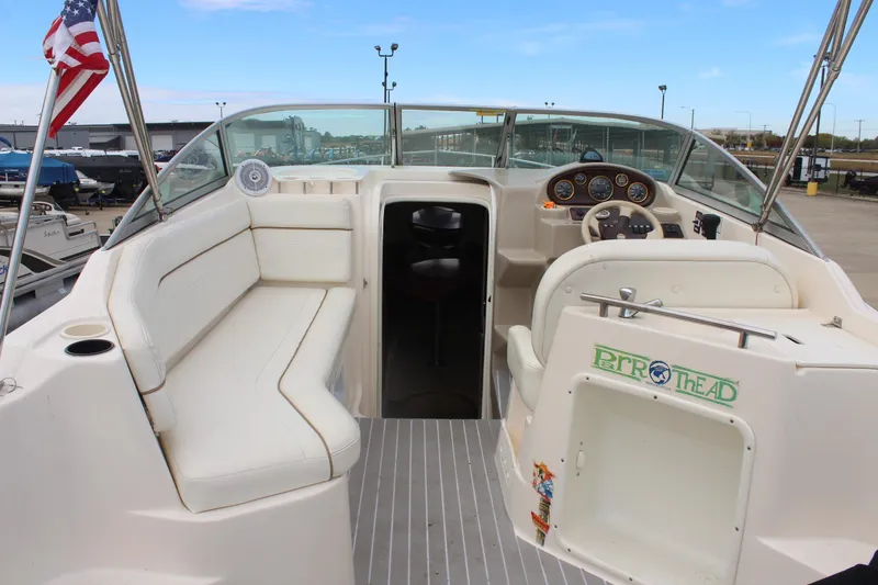 Slide: The Image of 2002 Rinker Fiesta Vee 250 boat interior with seating and steering wheel, docked outdoors. - 8