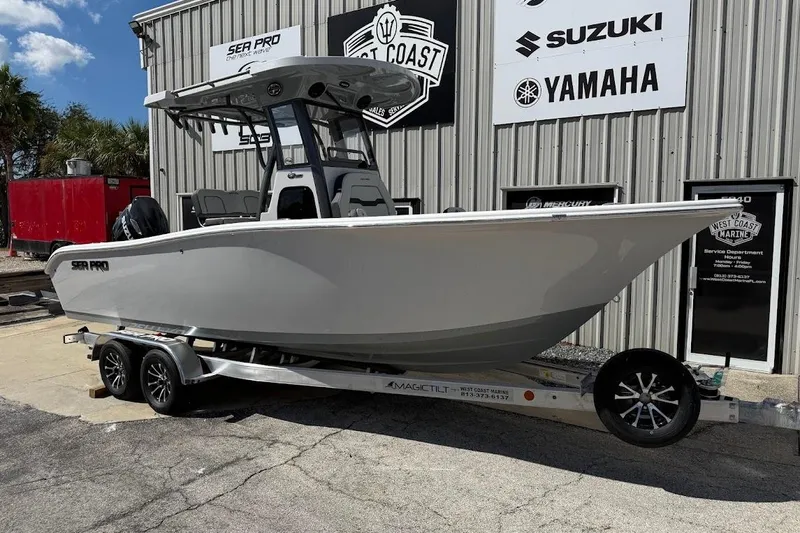The Image of 2026 Sea Pro 242 Center Console boat on trailer outside marine dealership. - 1