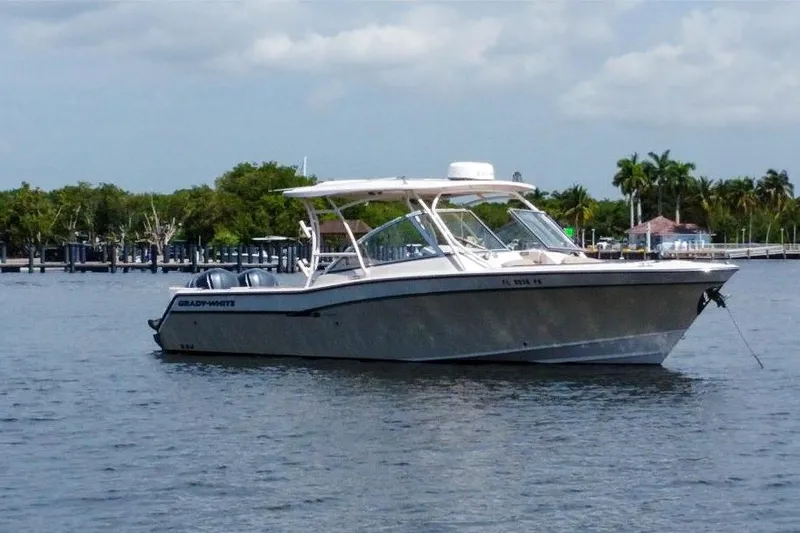 Slide: The Image of 2014 Grady-White Freedom 307 boat anchored on calm water with lush greenery background. - 3